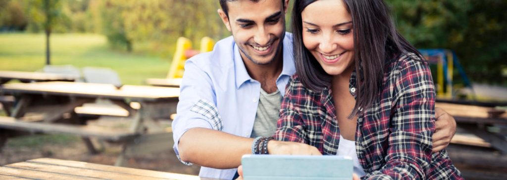 Young multi ehtnic couple in love using a digital tablet at the park.